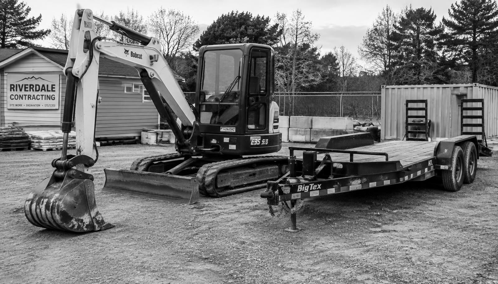 A compact excavator and trailer in a contractor’s yard